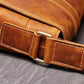 Brown leather messenger bag showing stitching detail and shoulder strap buckle