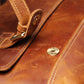 Closeup view of brown leather messenger bag showing magnetic snap button