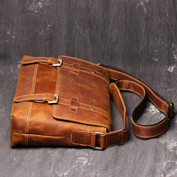 side view of brown leather messenger bag showing buckles and belts