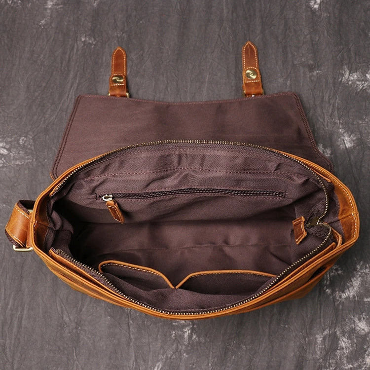 Top view of brown leather messenger bag showing open with zippers and storage