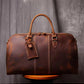 Front view of brown leather duffel bag showing stitching detail and luggage tag