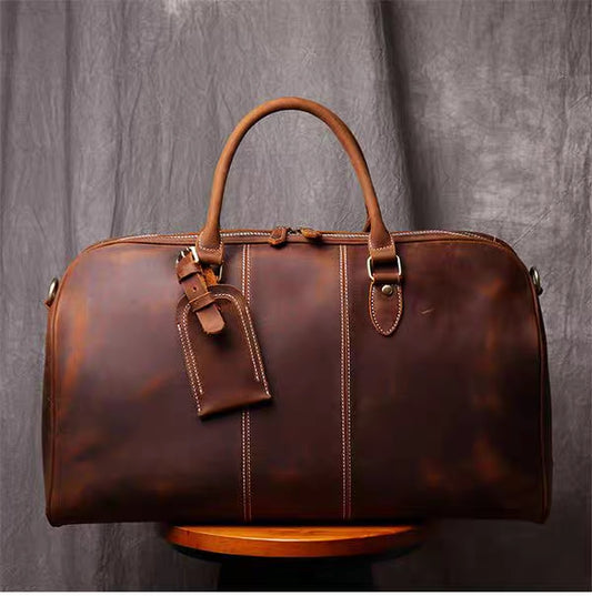 Front view of brown leather duffel bag showing stitching detail and luggage tag