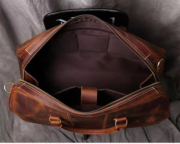 Top view of brown leather duffel bag with open zipper showing inside