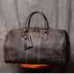 Front view of dark coffee color leather duffel bag showing stitching detail handles and luggage tag strap