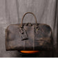 Front view of dark coffee color leather duffel bag showing stitching detail handles and luggage tag
