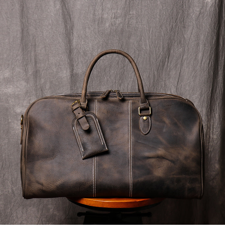 Front view of dark coffee color leather duffel bag showing stitching detail handles and luggage tag